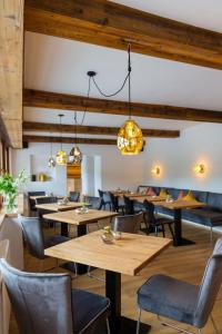 un restaurant avec des tables en bois, des chaises et des lumières dans l'établissement Hotel Alpin Tyrol - Kitzbüheler Alpen, à St. Johann in Tirol