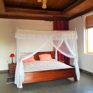 sypialnia z łóżkiem z baldachimem i pomarańczowymi poduszkami w obiekcie Maison de Passage - Isaro Passage House - Vacation Rental In Kigali w mieście Kigali