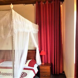 sypialnia z czerwonymi zasłonami i łóżkiem z baldachimem w obiekcie Maison de Passage - Isaro Passage House - Vacation Rental In Kigali w mieście Kigali