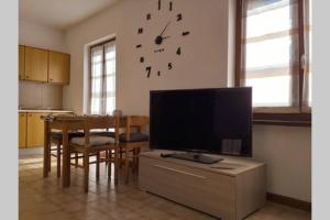 ein Wohnzimmer mit einem TV und einem Tisch mit einer Uhr in der Unterkunft VIVI SERENO, uno stile si vita! in Grosio