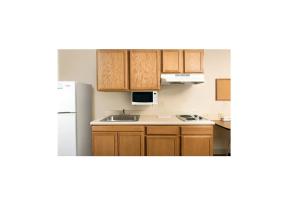 a kitchen with wooden cabinets and a white refrigerator at WoodSpring Suites Fort Worth Forest Hill in Forest Hill