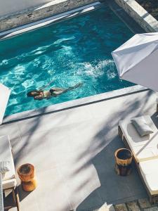 Eine Frau, die mit einem Regenschirm in einem Pool schwimmt. in der Unterkunft Charisma Boutique Hotel in Parga