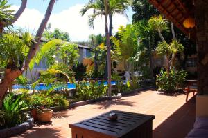 a patio with a table and palm trees and a pool at Xin Chao Hotel in Mui Ne