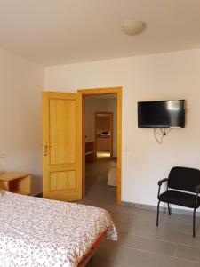 1 dormitorio con 1 cama y TV en la pared en Apartamento privado en una zona tranquila y próxima al aeropuerto TF norte y a la ciudad de San Cristóbal de la Laguna . en La Laguna