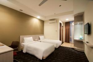 ein Hotelzimmer mit zwei Betten und einem Fernseher in der Unterkunft Scott Hotel KL Sentral in Kuala Lumpur