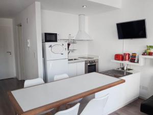 a white kitchen with a table and a refrigerator at Alquiler zona Belgrano Hospital Fleni y cancha de River in Buenos Aires