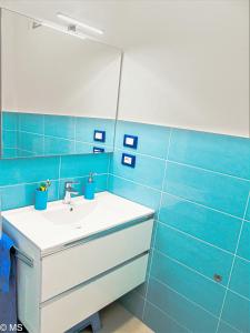 ein blaues Badezimmer mit einem Waschbecken und einem Spiegel in der Unterkunft Pietra Home, posto auto, AC ,WIFI, 150mt dal mare in Pietra Ligure