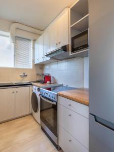 una cucina con armadietti bianchi e lavastoviglie di Four Seasons Sea View Apartment ad Atene