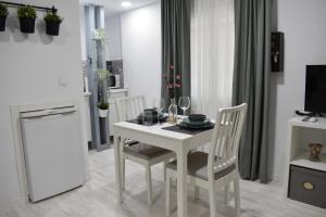 une cuisine avec une table et des chaises blanches ainsi qu'une télévision dans l'établissement Nice & Cool Studio, à Torremolinos