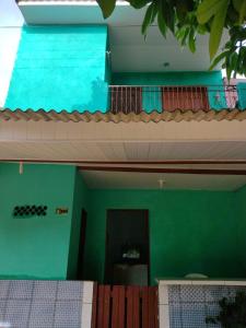 a bedroom with a green wall and a balcony at Pousada Sombra do Jambeiro in Alter do Chao