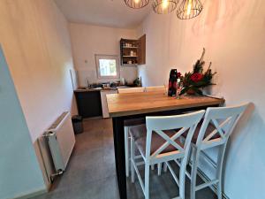 a kitchen with a wooden table and two white stools at Luxor Apartmani 2 in Vrnjačka Banja