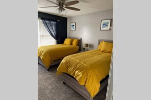 two beds in a bedroom with yellow bedding at Entire residential home -Omaha in Omaha