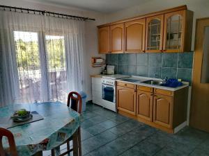 eine Küche mit Holzschränken, einem Tisch und einer Spüle in der Unterkunft Apartman Čanaki Splitska in Splitska