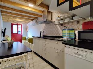uma cozinha com armários brancos e um balcão preto em La Casita de la Ribeira Sacra em Monforte de Lemos