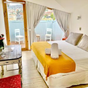 a bedroom with a large bed and a table at Escalera al Puerto Guest House in Valparaíso
