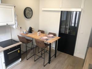 a kitchen with a table with chairs and a clock on the wall at Les Jardins Des Chambrettes in Clermont-Ferrand