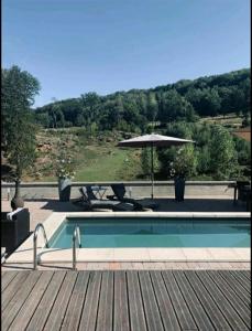 ein Pool mit einem Sonnenschirm neben einer Holzterrasse in der Unterkunft Repos et convivialité, wellness, spa, sauna, piscine in Schorbach