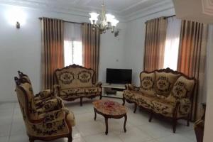 a living room with two chairs and a tv at Résidence Jeanne à Yaoundé Odza Messamengo in Yaoundé