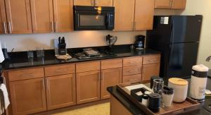 a kitchen with wooden cabinets and a black refrigerator at National at Loudoun in Ashburn