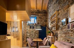 a room with a stone wall and a table and chairs at Story Studio Piódão - Heritage in Piódão