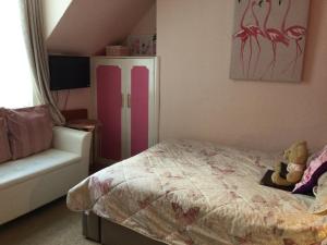 a bedroom with a bed and a white chair at Arun Sands Rooms in Littlehampton