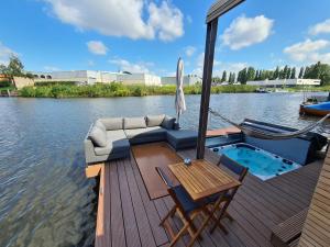a boat with a couch and a table on the water at Wikkelboats @ Tramkade Den Bosch in Orthen