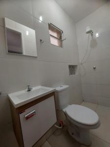 um banheiro com vaso sanitário, pia e espelho em Aluga-se por temporada em Vitória mais 29 fotografias