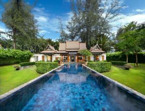 a swimming pool in front of a house at Banyan Tree Phuket in Bang Tao Beach