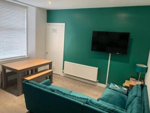 a living room with a couch and a tv on a green wall at Woodvale Flat, Renton, Loch Lomond in Renton