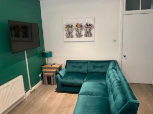 a living room with a green couch in a room at Woodvale Flat, Renton, Loch Lomond in Renton