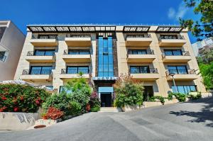 a large building with flowers in front of it at Hotel & Apartments HEC Residence in Sveti Stefan