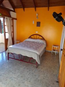 1 dormitorio con 1 cama con pared de color naranja en VILLA BETTY, en Anapoima