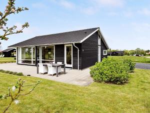 uma casa preta com um deque com uma mesa e cadeiras em 7 person holiday home in Nordborg em Nordborg
