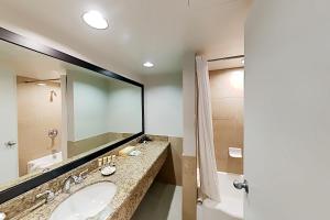 a bathroom with a sink and a mirror at Aqua Palms Waikiki Ocean View Lanai Parking Included in Honolulu