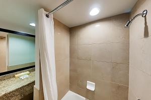 een badkamer met een douche met een douchegordijn bij Aqua Palms Waikiki Ocean View Lanai Parking Included in Honolulu