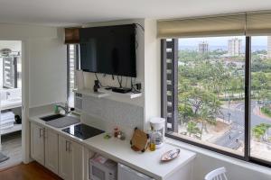 a kitchen with a flat screen tv and a large window at Hawaiian Monarch 1603 condo in Honolulu