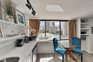 a kitchen with a glass table and blue chairs at Hawaiian Monarch 805 condo in Honolulu