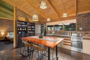 eine Küche mit einem Holztisch und einigen Stühlen in der Unterkunft Black Pearl - Aldinga Beach - C21 SouthCoast Holidays in Aldinga Beach