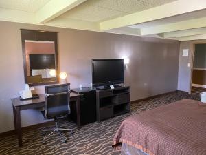a hotel room with a bed and a desk and a television at Economy Inn North Randall in North Randall