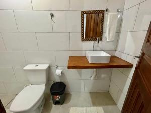 Un baño con inodoro, lavabo y espejo. en Pousada Aquarela, en Caraíva