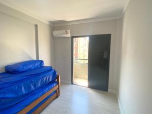 una camera da letto con un letto blu e una finestra di Apto a 2 min a Pé da Praia - Edificio Monte Carmel a Guarujá