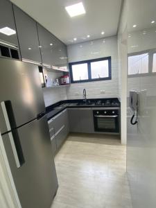 una cucina con frigorifero in acciaio inox e lavello di Apto a 2 min a Pé da Praia - Edificio Monte Carmel a Guarujá
