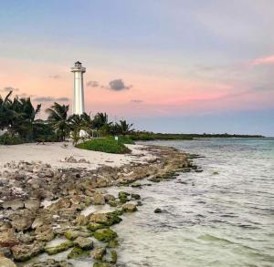 a lighthouse on the shore of a beach with the ocean at Hostal Jardin in Mahahual
