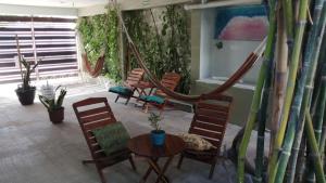 a living room with chairs and a table and a hammock at Hostal Jardin in Mahahual