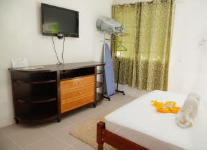 a room with a bed and a dresser with a television at Wanigi Guesthouse in Punta Gorda