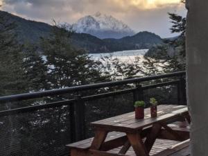 a wooden picnic table on a balcony with a snow covered mountain at Albanta casa con costa en Bariloche in San Carlos de Bariloche