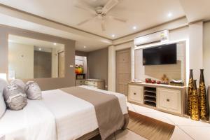 a bedroom with a large bed and a flat screen tv at Rocky's Boutique Resort - Veranda Collection Samui in Lamai