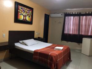 1 dormitorio con 1 cama y una pintura en la pared en Hostal Bellagio en Guayaquil