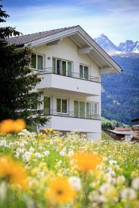 ein Haus auf einem Hügel mit einem Blumenfeld in der Unterkunft Alpina Appartements in Nauders