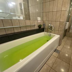 a bath tub filled with green water in a bathroom at Sapporo Classe Hotel in Sapporo